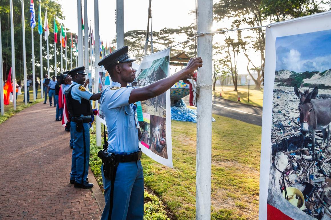 UNON Security staff setting up a photo exhibition at the main row of member state flags hoisted at the walkway connecting the main entrance of the United Nations Office at Nairobi complex.