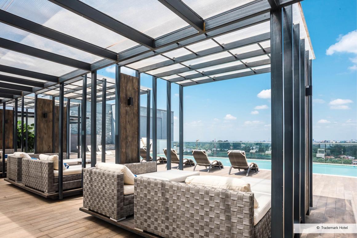 Vue du vestibule d’un hôtel situé à proximité du complexe de l’ONUN, comprenant une piscine extérieure entourée de palmiers et de chaises longues