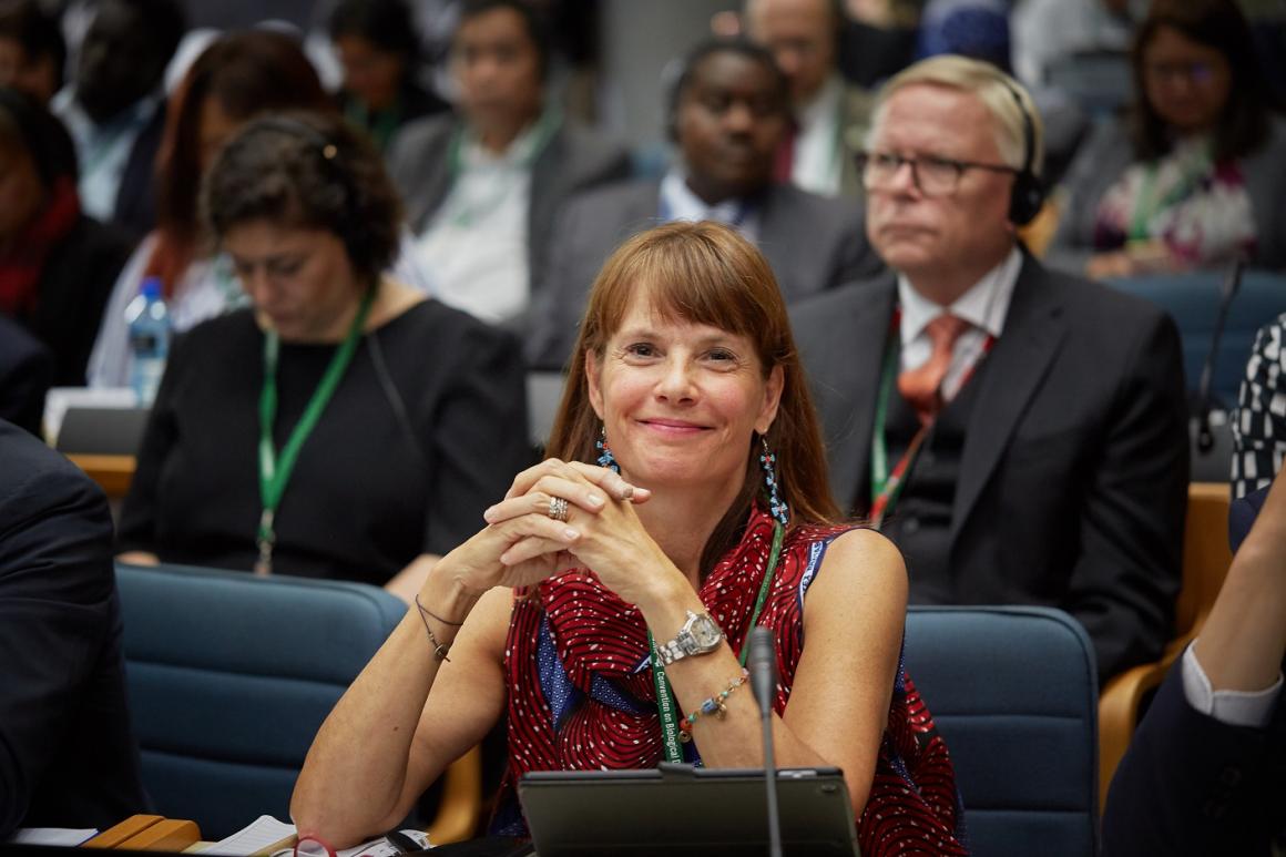 A smiling woman delegate listening attentively to the proceedings during a conference at the UNON complex