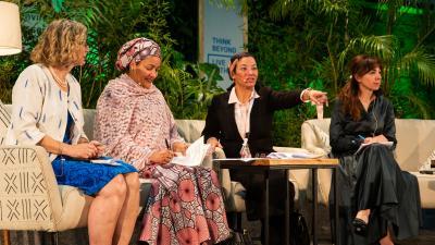 Four women, including Amina J. Mohammed, on a panel. One points, another holds papers.