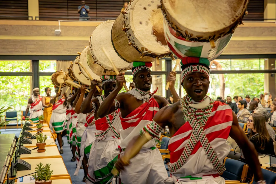 A line of performers with drums on their heads